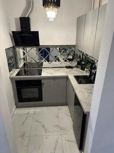a kitchen with white marble counter tops and a stove at Imperial Apartament in Gniezno