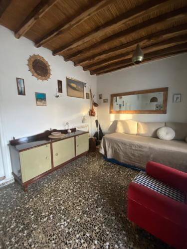 a bedroom with a bed and a red couch at Evnomia Cycladic Home from 1912 in Mélanes