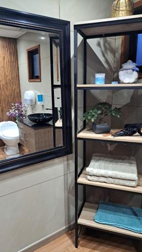 a bathroom with a mirror and a shelf with towels at Mary y Luis in Coihaique