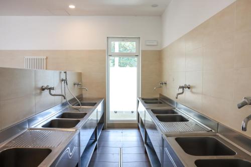a large kitchen with sinks and a window at Camping Al Porto - Mini Glamping & Mobile Homes in Nago-Torbole