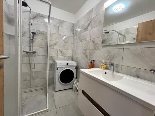 a bathroom with a shower and a sink and a washing machine at iHome Apartman 4 in Pécs