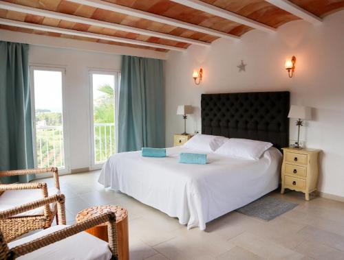 a bedroom with a large white bed and windows at Hotel Rural Can Maries in Puerto de San Miguel