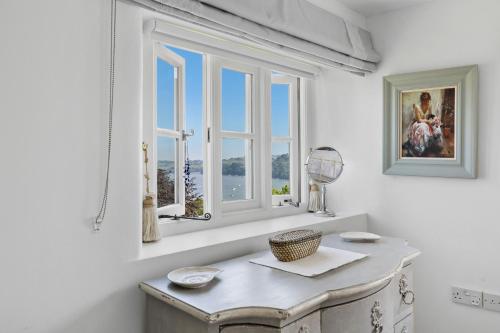 a white room with a table and two windows at Dart View Cottage - A Stunning Riverside Escape in the Heart of South Devon in Dittisham