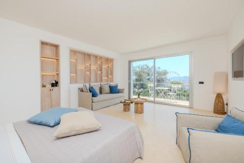 a white bedroom with two beds and a living room at Antares Rooms and Suites in Olbia