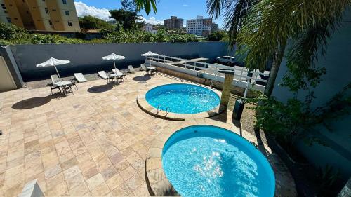 two swimming pools on a patio with tables and umbrellas at Atlas Beach Hotel in Fortaleza