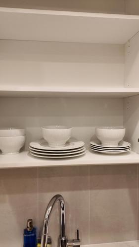 a kitchen shelf with bowls and plates on it at Luxury Heart of the city in Surrey