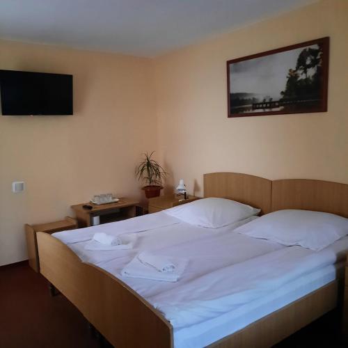 a bedroom with a bed with white sheets and a flat screen tv at Pensiunea Casa Vulkan in Ocna Sibiului