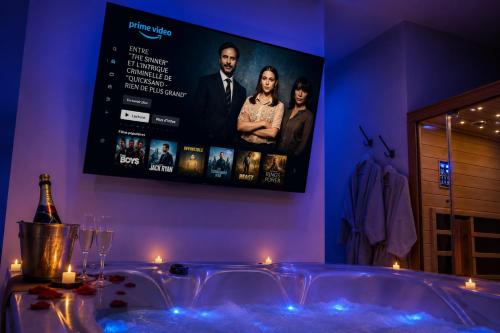 a bath tub in a room with a tv on the wall at Eaux Spa in Rouen