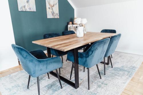 a dining room with a wooden table and blue chairs at Ferienwohnung Düring in Loxstedt