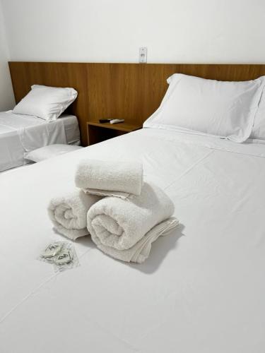 two white towels are stacked on a white bed at Chalés Areias in Barreirinhas