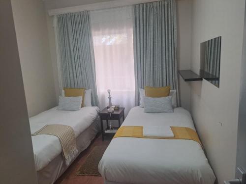 two beds in a small room with a window at Beach Hive 2 in Walvis Bay