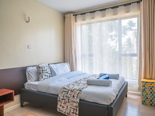 a bedroom with a bed and a large window at Easy Stay Rongai Poolside 2BR near Karen WiFi and Netflix in Ongata Rongai 