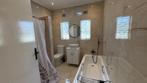 a bathroom with a tub and a toilet and a mirror at Bella Vista in Edenvale