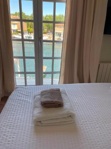 a bed with towels on it with a large window at Petite maison de pecheur in Grimaud