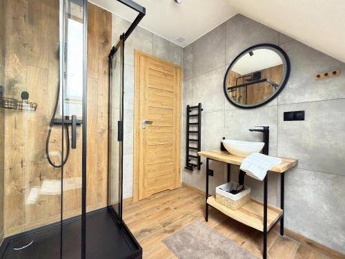a bathroom with a shower and a sink and a mirror at Apartamenty 242E in Chochołów