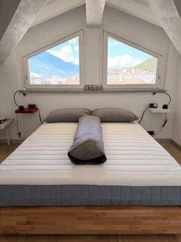 a large bed in a room with two windows at Casa Cocci in Aosta
