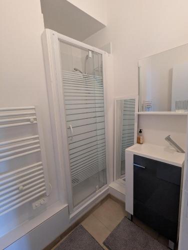 a bathroom with a glass shower and a sink at Appartement du parc in Ambert