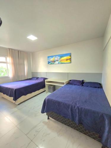a bedroom with two beds and a desk and a table at Praia Morro Katia apartamentos - Edificio Franklin Storck in Guarapari