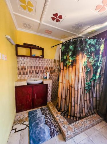 a bathroom with a shower curtain and a sink at Mnchunge's Residence in Kikambala