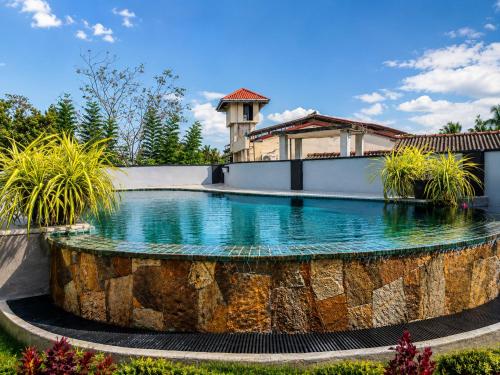 a swimming pool with a stone fountain in a yard at The Urban Stay in Galle