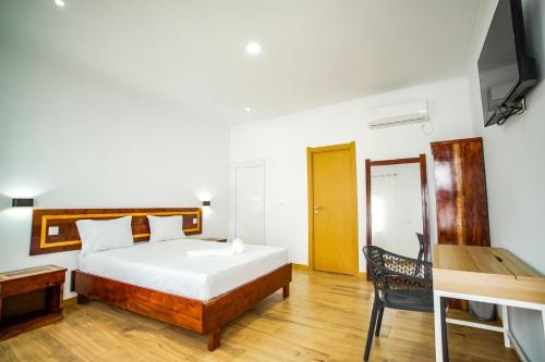a bedroom with a bed and a desk and a television at Hotel Santos Silva in São Tomé
