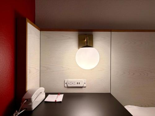 a room with a desk with a phone and a light at Ramada Limited Bloomington IL I-74/I-55 in Bloomington
