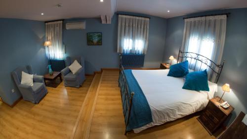 a bedroom with a bed with blue walls and blue pillows at Hotel Venta Magullo in La Lastrilla