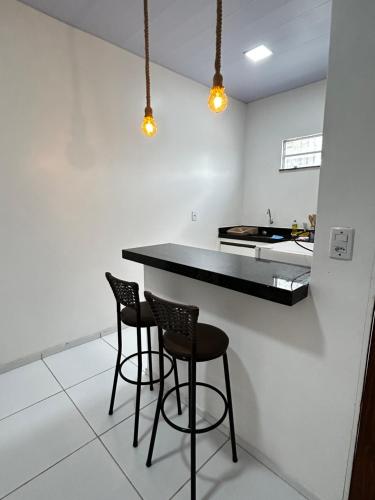 a kitchen with two bar stools and a counter at Chalés Areias in Barreirinhas