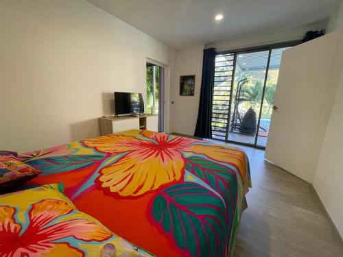 a bedroom with a bed with a colorful blanket at Tahiti Green Lodge in Punaauia