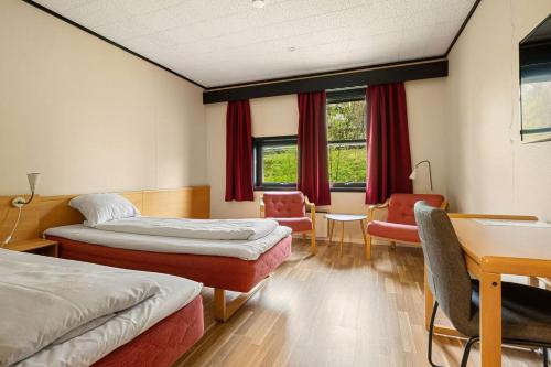 a room with two beds and a desk and chairs at Ørnes Hotell in Ørnes