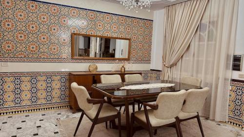 a dining room with a table and chairs and a mirror at Dar Joud in Gabès