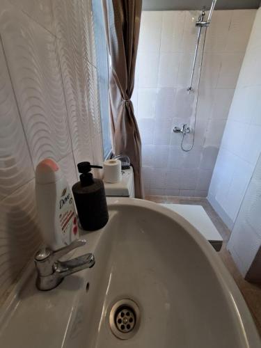 a white sink with a bottle of soap on top of it at Nic's Inn in Freetown