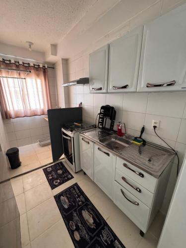 a small kitchen with white cabinets and a sink at Apartamento 2 quartos ,Mobiliado em Sumare SP in Sumaré