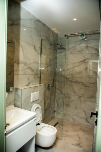 a bathroom with a shower and a toilet and a sink at HOTEL CENTERPOINT Tirana in Tirana