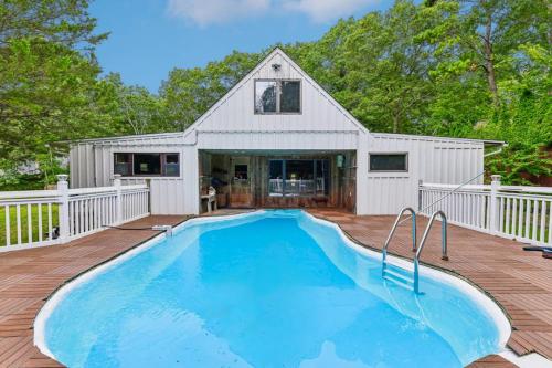 ein Swimmingpool auf einer Terrasse mit einem Haus in der Unterkunft Tree Canopy Oasis in East Quogue