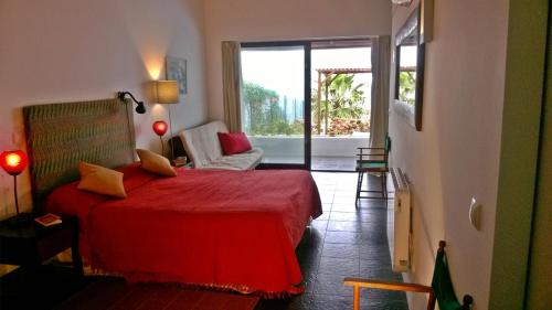 a bedroom with a red bed and a sliding glass door at QVA - Quinta Velha das Amoreiras in Vila Franca do Campo