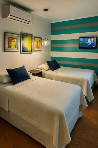 a hotel room with two beds and a tv on the wall at Hotel Verona in San Pedro Sula