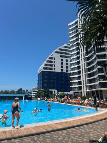a group of people swimming in a swimming pool at Квартира у моря с бассейном in Batumi