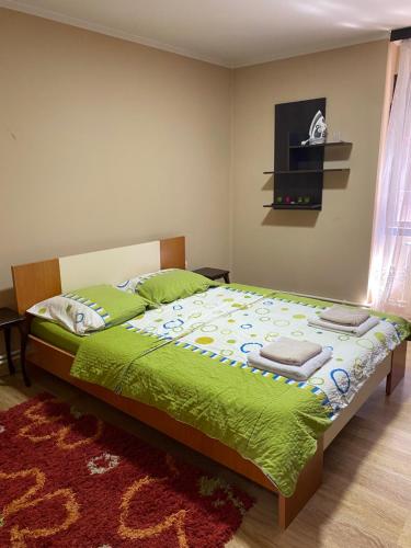 a bedroom with a bed with green sheets and a rug at Nena in Veliko Gradište