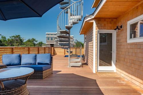 a deck with a blue couch and a staircase at Poolside Chic by the Sea in Ocean Bay Park