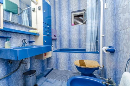 a blue bathroom with a toilet and a sink at Rooms Roza in Vrboska