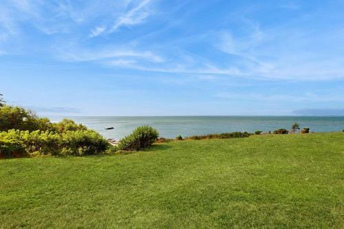 a green field with the ocean in the background at North Fork Waterfront Gem in East Marion