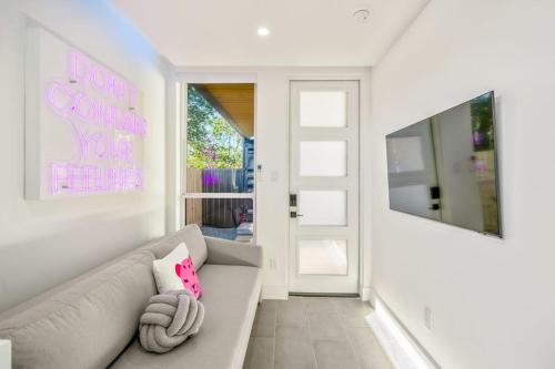 a white living room with a couch and a pink pillow at Blueberry Container at EADO Juicebox in Houston