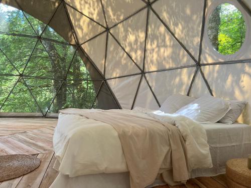 a bedroom with a bed in a glass wall at Dôme en forêt in Saint-Just