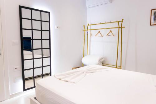 a white bedroom with a bed and a mirror at Vila Goxhaj in Sarandë