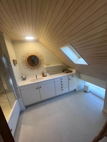 an attic bathroom with a sink and a mirror at Charmante maison rénovée in Fernelmont