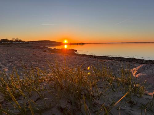 a sunset on a beach with the sun setting at Nordlicht, 1-Zimmer mit Meerblickbalkon 500 m zum Strand in Westerholz