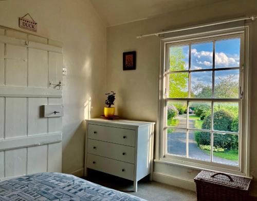 a bedroom with a window and a dresser and a bed at Stylish Countryside Loft near Silverstone-Bicester in Buckingham