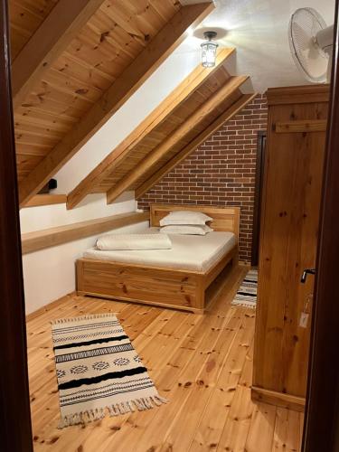 a bedroom with a bed in a loft with wooden floors at Casa de Piatra in Porumbacu de Sus