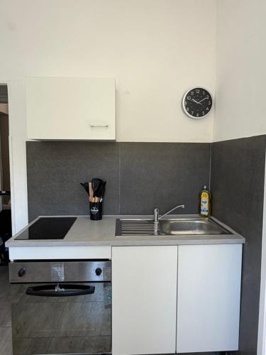 a kitchen with a sink and a clock on the wall at Le petit port de boucain in Port-de-Bouc